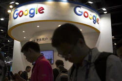 In this April 27, 2017 photo, visitors use their smartphones in front of a booth for Google at the Global Mobile Internet Conference in Beijing.