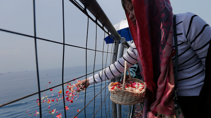 A relative sprinkles flowers for victims in the crashed Lion Air flight 610 aboard an Indonesia Navy ship in the waters where the airplane is believed to have crashed in Tanjung Karawang, Indonesia, Tuesday, Nov. 6, 2018.