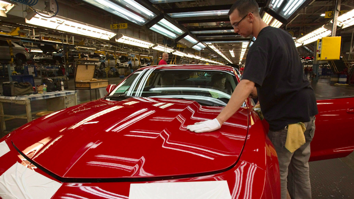 In this June 10, 2011, file photo, a worker checks the paint on a Camaro at the GM factory in Oshawa, Ontario.