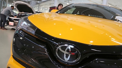 In this Nov. 13, 2017, photo, visitors take a look at Toyota cars at the automaker's showroom in Tokyo.