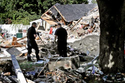 In this Sept. 21, 2018 file photo, fire investigators pause while searching the debris at a home which exploded following a gas line failure in Lawrence, Mass.