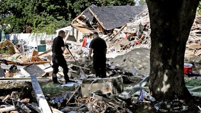 In this Sept. 21, 2018 file photo, fire investigators pause while searching the debris at a home which exploded following a gas line failure in Lawrence, Mass.