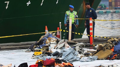 Port officials stand near debris from Lion Air Flight 610 that crashed into Java Sea, at Tanjung Priok Port in Jakarta, Indonesia, Friday, Nov. 2, 2018.