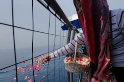 A relative sprinkles flowers for victims in the crashed Lion Air flight 610 aboard an Indonesia Navy ship in the waters where the airplane is believed to have crashed in Tanjung Karawang, Indonesia, Tuesday, Nov. 6, 2018.