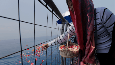 A relative sprinkles flowers for victims in the crashed Lion Air flight 610 aboard an Indonesia Navy ship in the waters where the airplane is believed to have crashed in Tanjung Karawang, Indonesia, Tuesday, Nov. 6, 2018.