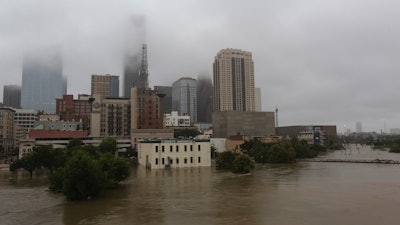 In this Monday, Aug. 28, 2017 file photo, floodwaters from Tropical Storm Harvey overflow from Buffalo Bayou in downtown Houston.