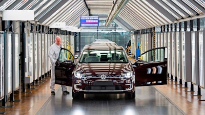 In this March 5, 2018 file photo, Roland Schulz makes the final check of an e-Golf electric car in Dresden, Germany.
