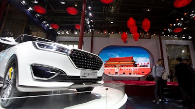 In this file photo taken Monday, April 25, 2016, visitors to Auto China 2016 stand near Zotye Auto's T300 SUV displayed in Beijing.
