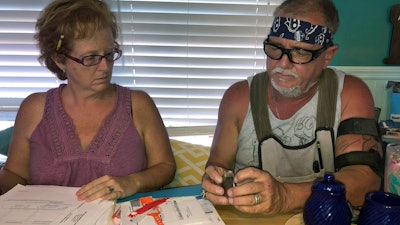In this Oct. 31 2018 photo, George and Brenda Davis look at his nerve stimulator and medical documents at their home in Milton, Fla.
