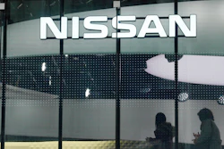 Visitors walk near the logo of Nissan at a Nissan showroom in Tokyo, Thursday, Nov. 22, 2018.