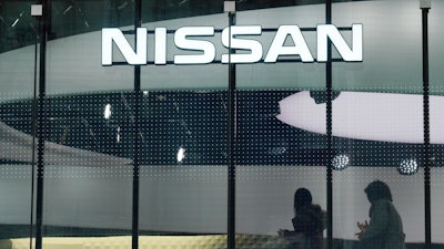 Visitors walk near the logo of Nissan at a Nissan showroom in Tokyo, Thursday, Nov. 22, 2018.