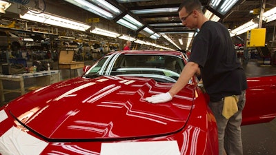 In this June 10, 2011, file photo, a worker checks the paint on a Camaro at the GM factory in Oshawa, Ontario.