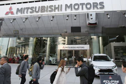 People walk past the headquarters of Mitsubishi Motors Corp. in Tokyo, Monday, Nov. 26, 2018.