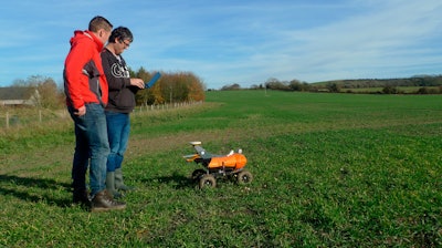 Joe Allnutt, left, and Thomas Burrell operate a farming robot named 'Tom' as part of a trial in East Meon, southern England.