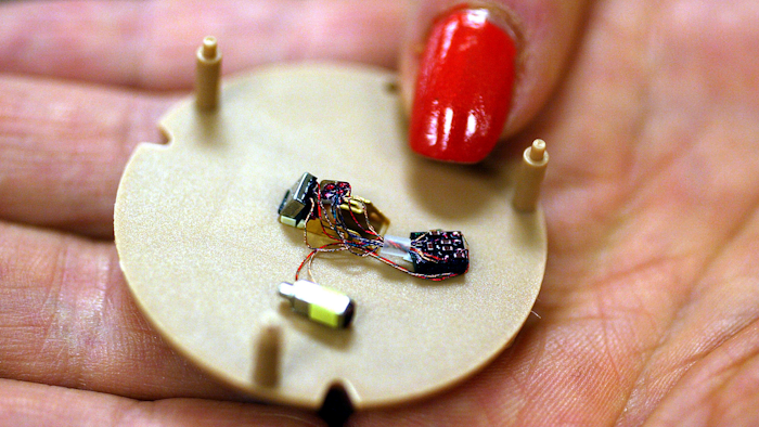 In this July 12, 2004, file photo, a woman holds a hearing aid that uses artificial intelligence in Somerset, N.J.