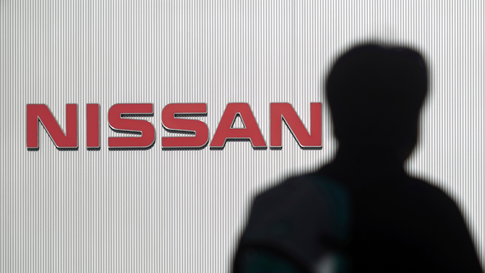 In this Nov. 21, 2018, file photo, a man walks past the logo of Nissan Motor Co. near Tokyo.