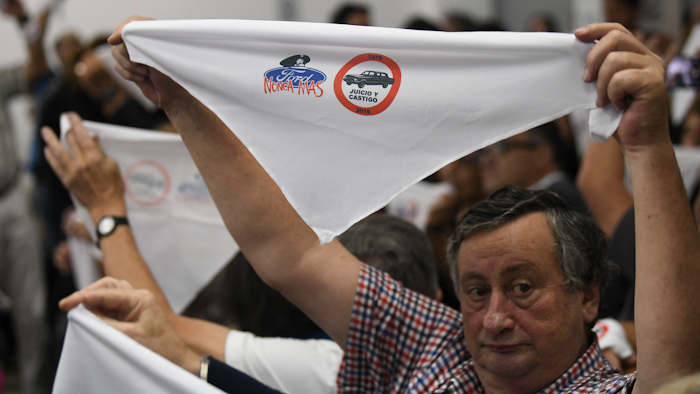 Family members of ex-Ford Motor Co. employees hold up handkerchiefs that are stamped with a message that reads in Spanish: “Ford never more.”