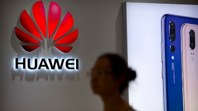 In this July 4, 2018, file photo, a shopper walks past a Huawei store at a shopping mall in Beijing.