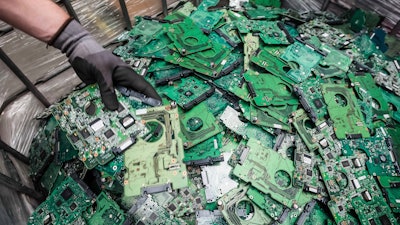 In this photo taken on July 13, 2018, a worker throws components of electronic elements into a bin at the Out Of Use company warehouse in Beringen, Belgium.