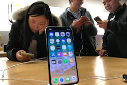 In this Nov. 6, 2017, file photo, shoppers check out the iPhone X at an Apple store in Beijing.