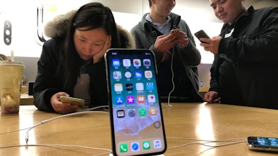 In this Nov. 6, 2017, file photo, shoppers check out the iPhone X at an Apple store in Beijing.