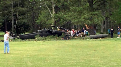 In this Monday, April 17, 2017 file photo, people examine an Army UH-60 Black Hawk helicopter after it crashed at the Breton Bay Golf and Country Club in Leonardtown, Md.