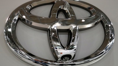 In this May 10, 2017, file photo a Toyota Land Cruiser is reflected on the emblem of Toyota Motor Corp. at a showroom in Tokyo.