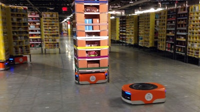 A robot moves under a stack of merchandise during a tour of an Amazon facility in Tracy, Calif., Nov. 30, 2014.