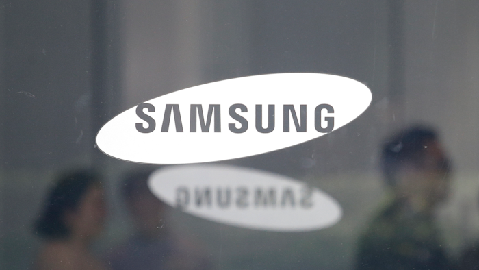 In this July 31, 2018 file photo, employees walk past logos of the Samsung Electronics Co. at its office in Seoul.
