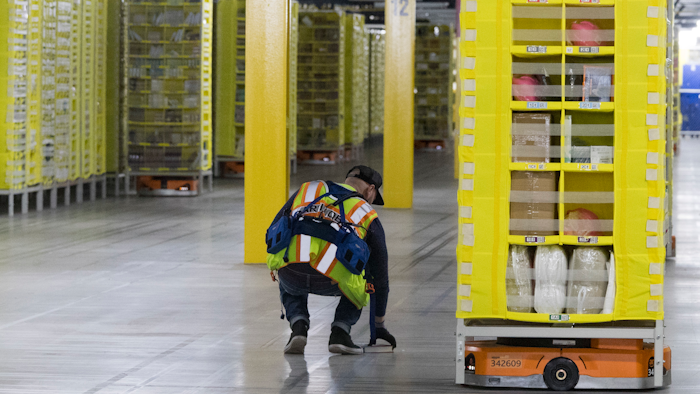 In this Dec. 5, 2018, photo, Artur Yilnaz retrieves a book that fell off a pod at the Amazon fulfillment center on Staten Island.