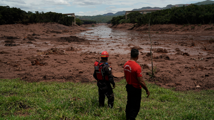Civil firefighters survey a destroyed rail bridge two days after a dam collapse in Brumadinho, Brazil, Sunday, Jan. 27, 2019.