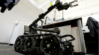 In this Aug. 28, 2018 photo a Centaur robot rests on a carpeted floor between desks at Endeavor Robotics in Chelmsford, Mass.