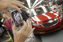 In this Sept. 8, 2010 file photo, auto worker Brenda Hedland takes a picture of the first Chevrolet Cruze to come off the assembly line at a ceremony in Lordstown, Ohio.