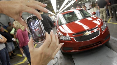 In this Sept. 8, 2010 file photo, auto worker Brenda Hedland takes a picture of the first Chevrolet Cruze to come off the assembly line at a ceremony in Lordstown, Ohio.