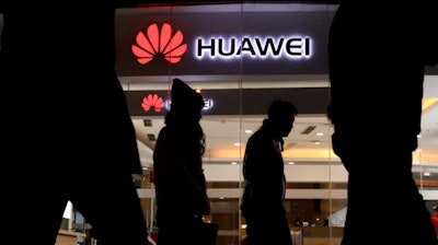 Pedestrians walk past a Huawei retail shop in Beijing Thursday, Dec. 6, 2018.