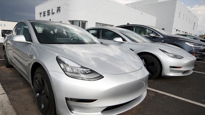 In this July 8, 2018, photo 2018 Model 3 sedans sit on display outside a Tesla showroom in Littleton, Colo.