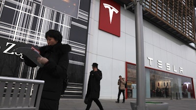 Residents walk past a Tesla store in Beijing, Monday, Jan. 7, 2019.