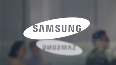 In this July 31, 2018 file photo, employees walk past logos of the Samsung Electronics Co. at its office in Seoul.