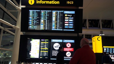 Passengers look at the departure board after planes were temporarily suspended at Heathrow Airport in London, Tuesday, Jan. 8, 2019.