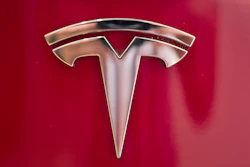 This Aug. 8, 2018, file photo shows a Tesla emblem on the back end of a Model S in the Tesla showroom in Santa Monica, Calif.