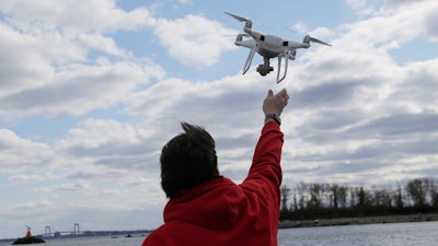 In this April 29, 2018, file photo, a drone operator helps to retrieve a drone after photographing over Hart Island in New York.