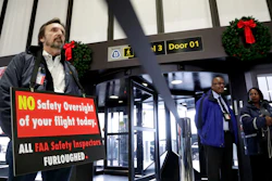 In this Tuesday, Jan. 8, 2019, file photo, FAA employee Michael Jessie holds a sign at Newark Liberty International Airport.