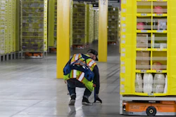 In this Dec. 5, 2018, photo, Artur Yilnaz retrieves a book that fell off a pod at the Amazon fulfillment center on Staten Island.