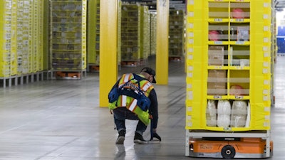 In this Dec. 5, 2018, photo, Artur Yilnaz retrieves a book that fell off a pod at the Amazon fulfillment center on Staten Island.