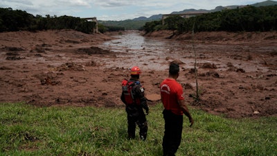 Civil firefighters survey a destroyed rail bridge two days after a dam collapse in Brumadinho, Brazil, Sunday, Jan. 27, 2019.