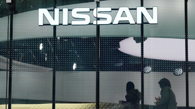 In this Nov. 22, 2018, file photo, visitors walk near the logo of Nissan at a showroom in Tokyo.