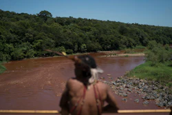 Hayo, chief of the Pataxo Ha-ha-hae indigenous community, stands over the Paraopeba River on a rail bridge near his village in Brumadinho, Brazil, Tuesday, Jan. 29, 2019.