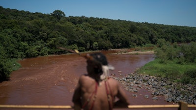 Hayo, chief of the Pataxo Ha-ha-hae indigenous community, stands over the Paraopeba River on a rail bridge near his village in Brumadinho, Brazil, Tuesday, Jan. 29, 2019.