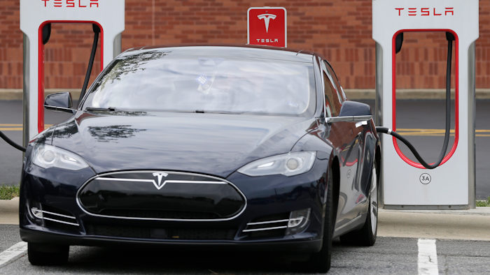 In this June 24, 2017, file photo, a Tesla Model 3 car recharges at at Cochran Commons shopping center in Charlotte, N.C.