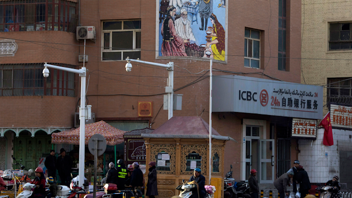 In this Nov. 5, 2017, file photo, residents pass by a security checkpoint and surveillance cameras mounted on a street in Kashgar in western China's Xinjiang region.